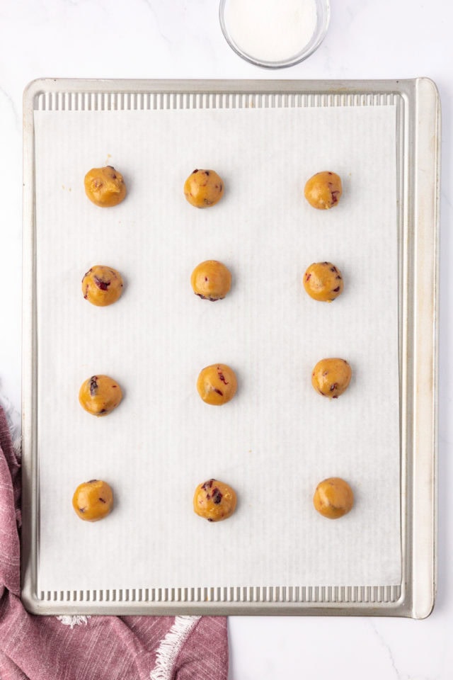 overhead view of macadamia butter cookie dough balls on a lined baking sheet