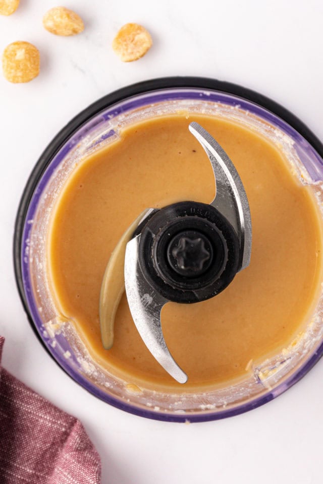 overhead view of macadamia butter in the bowl of a food processor