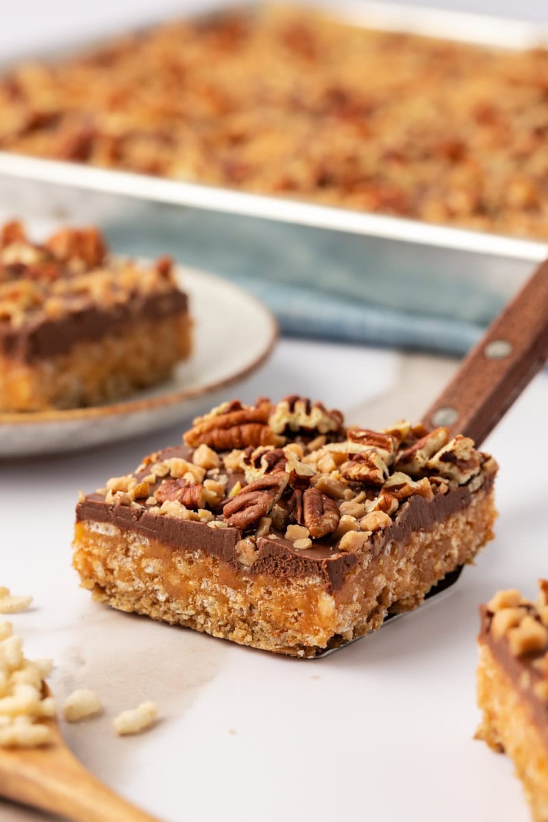 a chocolate peanut butter cereal bar on a cookie spatula with more bars in the background