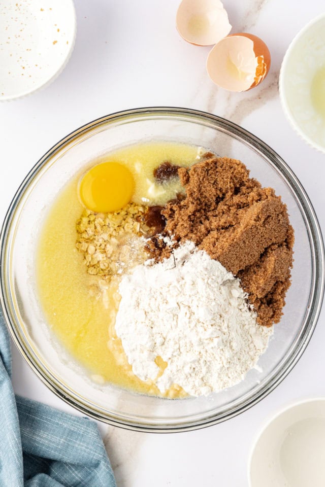 overhead view of a glass mixing bowl filled with crust ingredients for chocolate peanut butter cereal bars