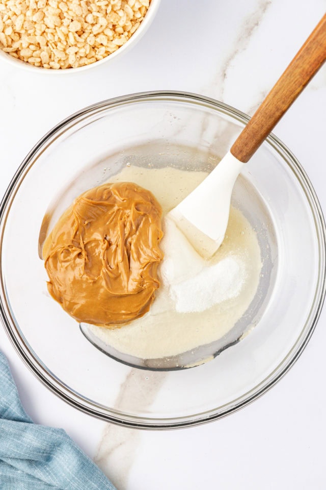 overhead view of peanut butter, sugar, and corn syrup in a glass mixing bowl