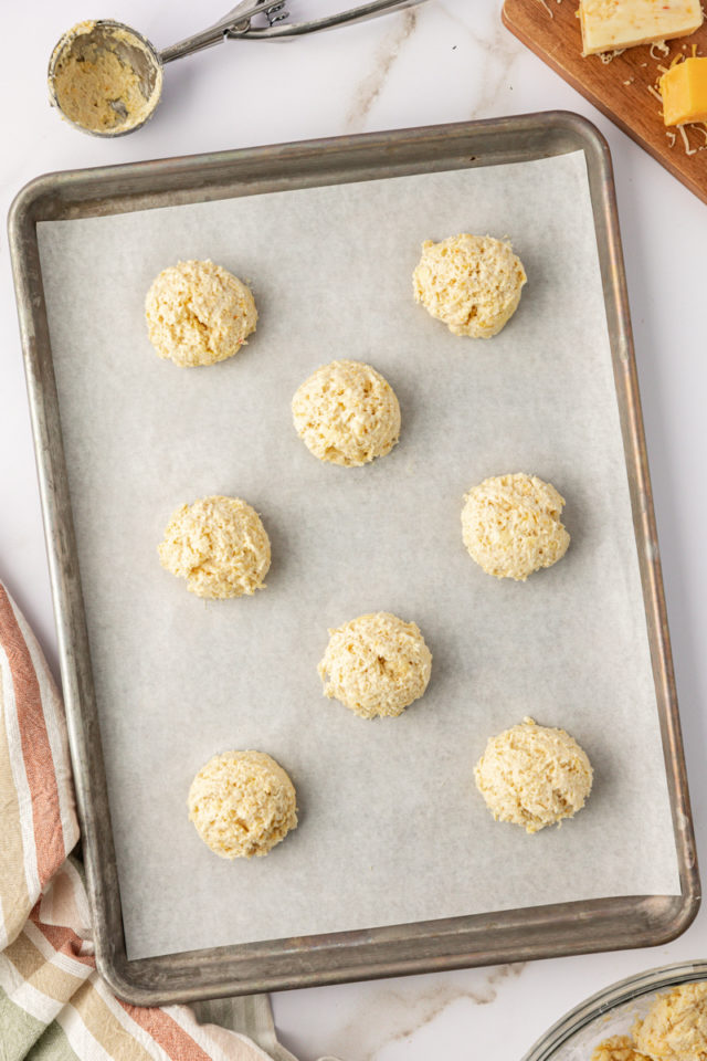 overhead view of three cheese biscuit dough portioned onto a baking sheet ready to go into the oven