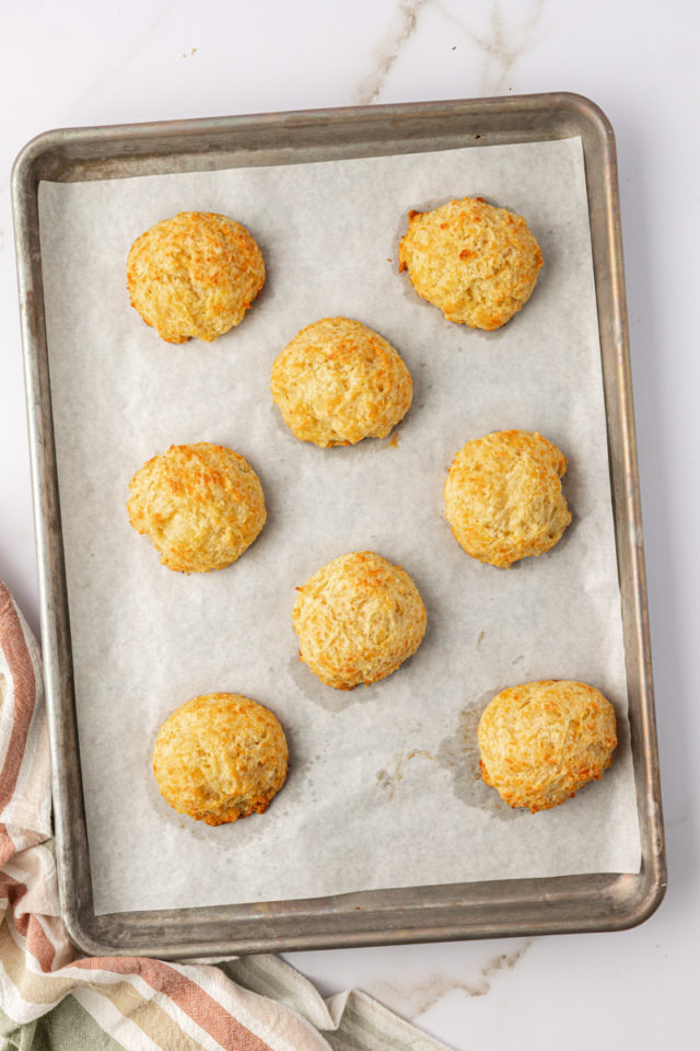 overhead view of freshly baked three cheese biscuits on a baking sheet