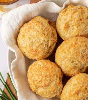overhead view of three cheese biscuits in a towel-lined bowl