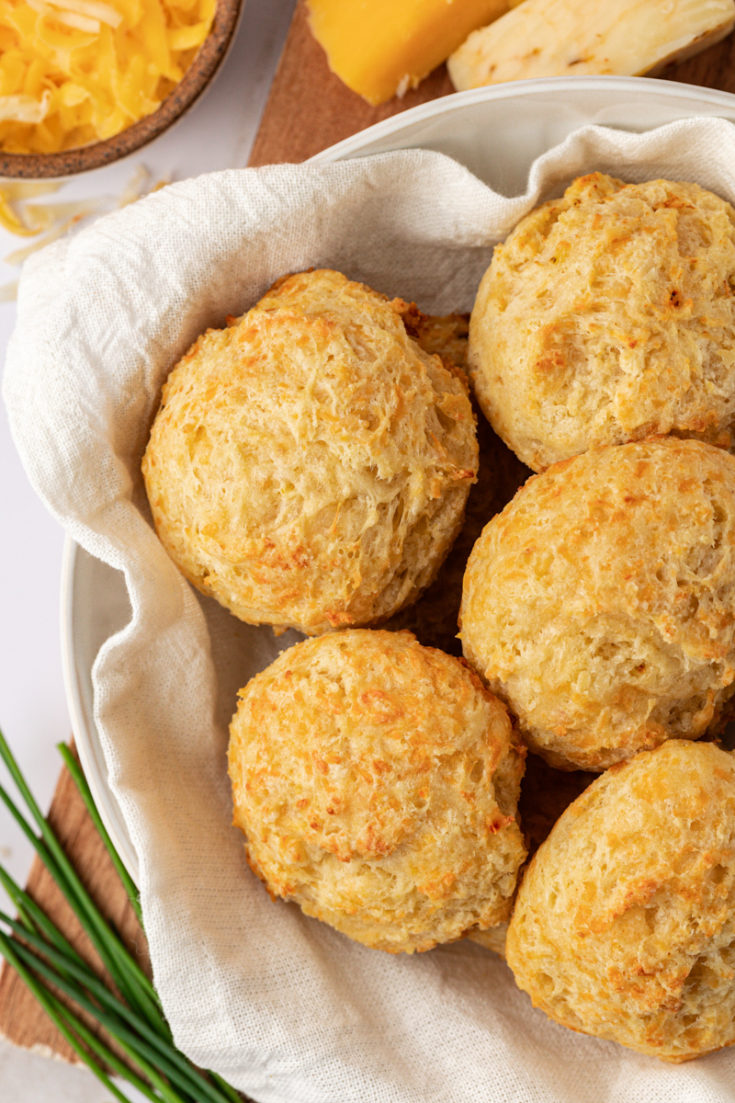 overhead view of three cheese biscuits in a towel-lined bowl