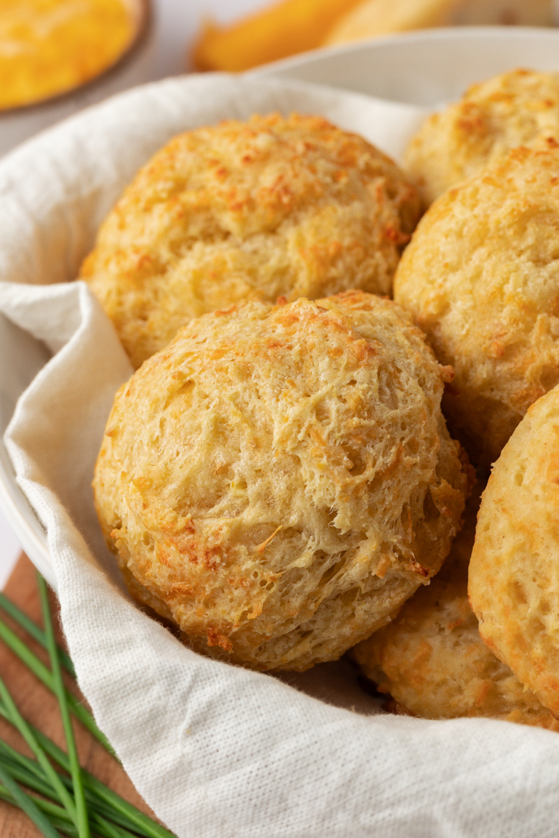 three cheese biscuits in a towel-lined bowl