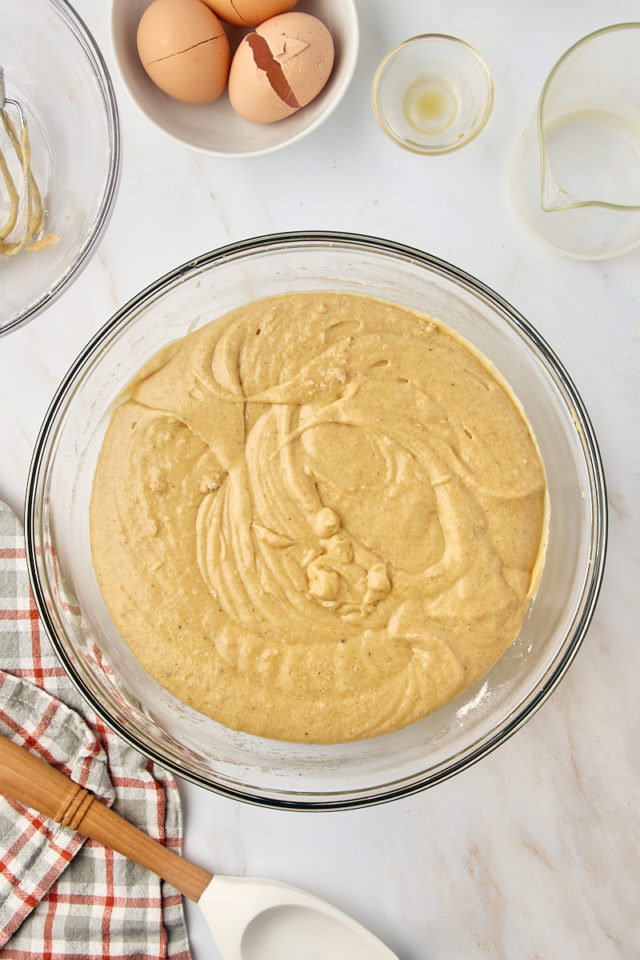 overhead view of mixed apple cider donut cake batter in a glass mixing bowl