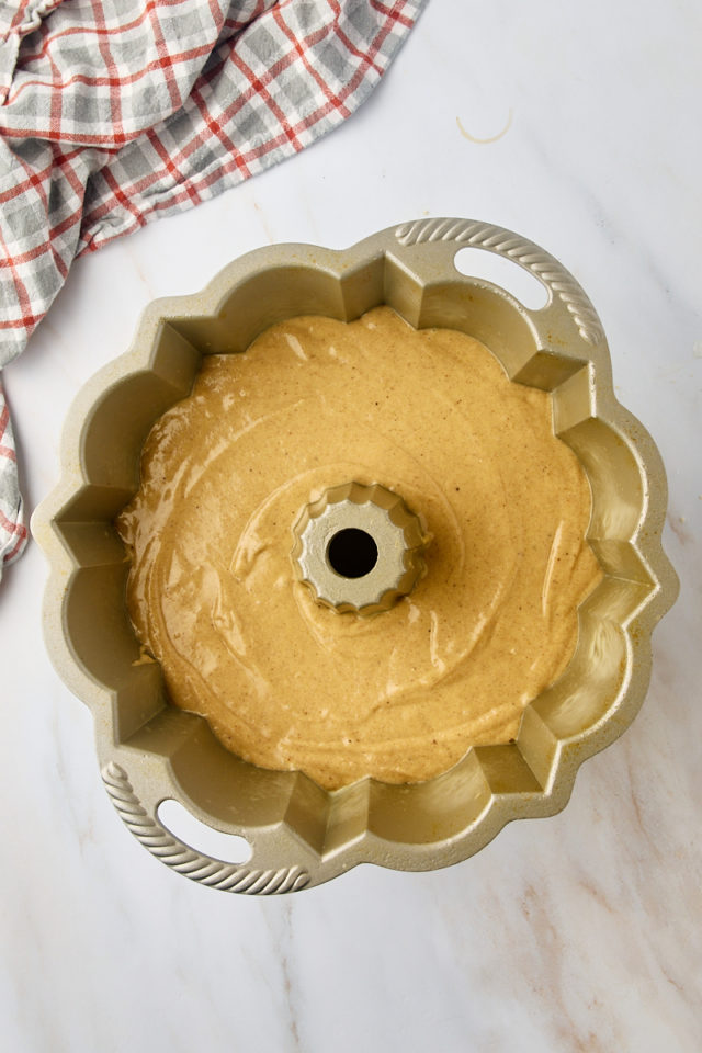 overhead view of apple cider donut cake batter in a Bundt pan ready to go into the oven