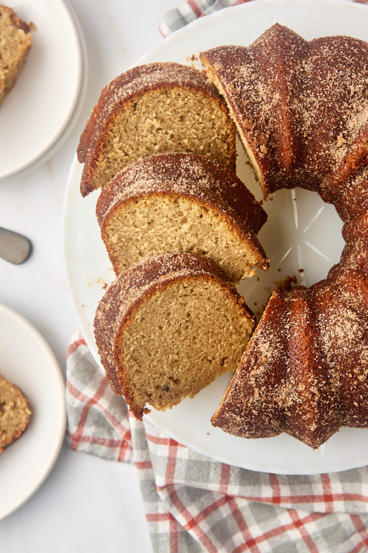 overhead view of partially sliced apple cider donut cake on a white cake plate