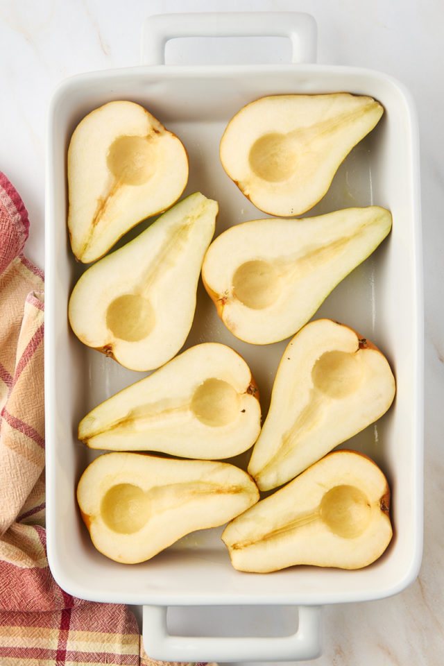 overhead view of halved and cored pears in a white baking dish