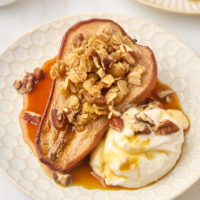 a baked pear served with Greek yogurt, maple syrup, and toasted pecans