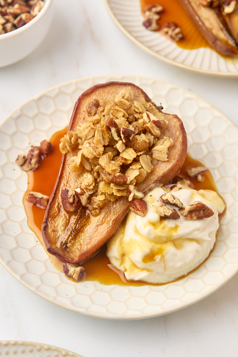 a baked pear served with Greek yogurt, maple syrup, and toasted pecans