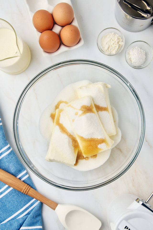 overhead view of cream cheese, sugar, vanilla, and salt in a glass mixing bowl