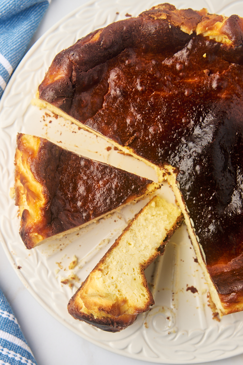 overhead view of partially sliced Basque cheesecake on a white serving plate