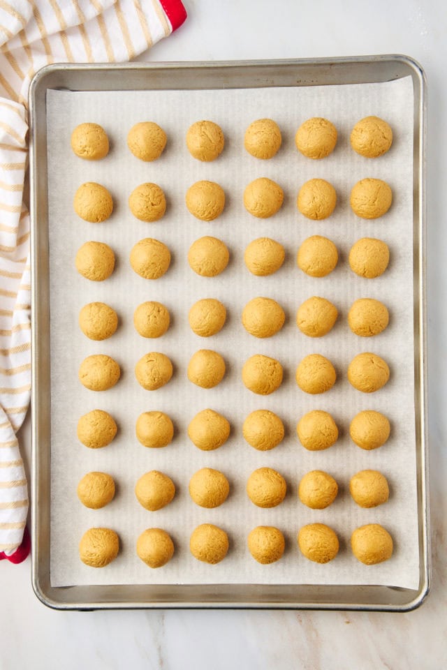 overhead view of peanut butter buckeyes mixture formed into balls on a lined baking sheet