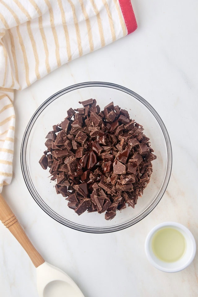 overhead view of chopped chocolate and vegetable oil in a glass mixing bowl