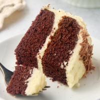 a slice of mahogany cake on a plate with a bite on a fork