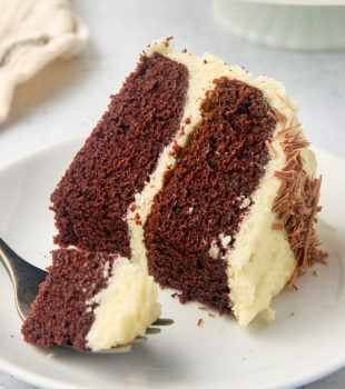 a slice of mahogany cake on a plate with a bite on a fork