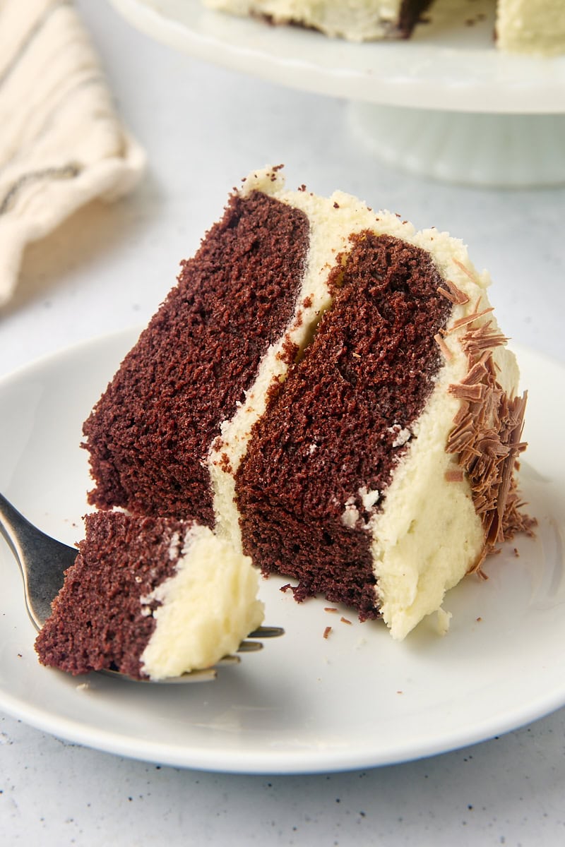 a slice of mahogany cake on a plate with a bite on a fork