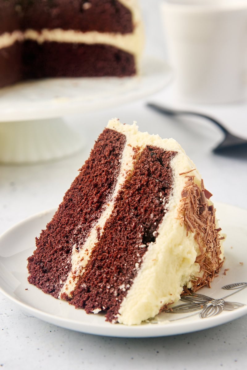 a slice of mahogany cake on a white plate with remaining cake in the background