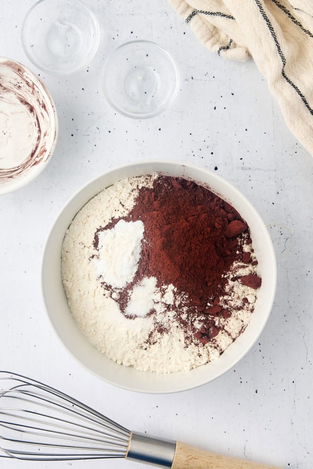 overhead view of cake flour, cocoa powder, baking soda, and salt in a white mixing bowl