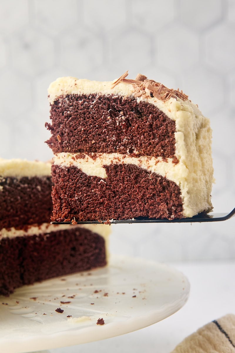 a slice of mahogany cake on a cake server lifting away from the remaining cake