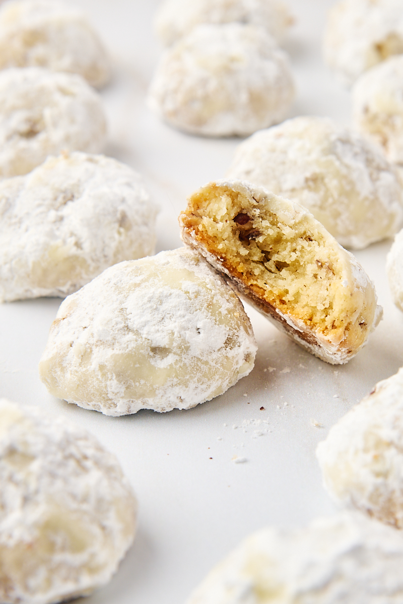 half of a snowball cookie propped on another cookie with even more cookies surrounding