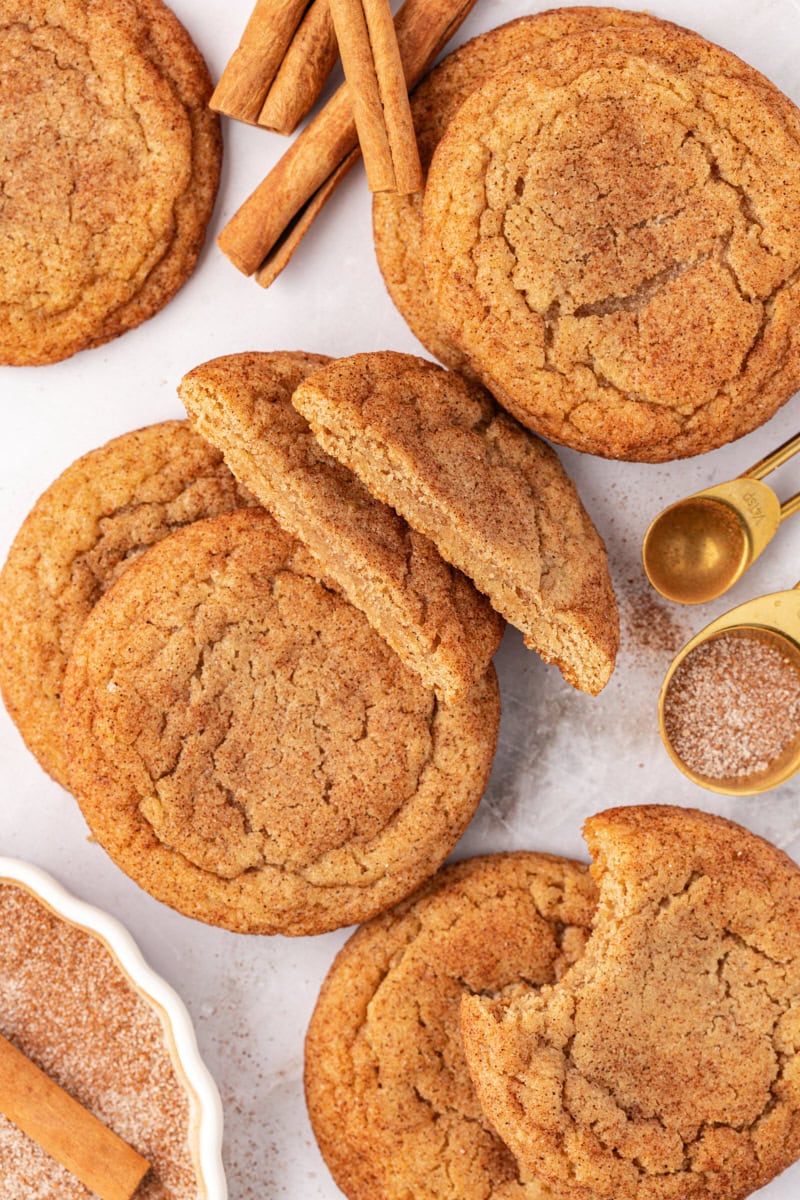 overhead view of brown butter snickerdoodles scattered on a countertop with cinnamon sticks