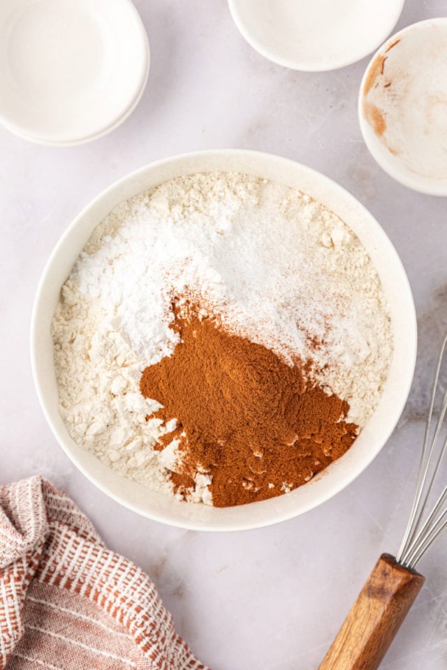 overhead view of flour, cream of tartar, baking soda, salt, and cinnamon in a mixing bowl