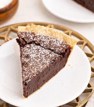 a slice of hot fudge pie with a sprinkling of confectioners' sugar on top