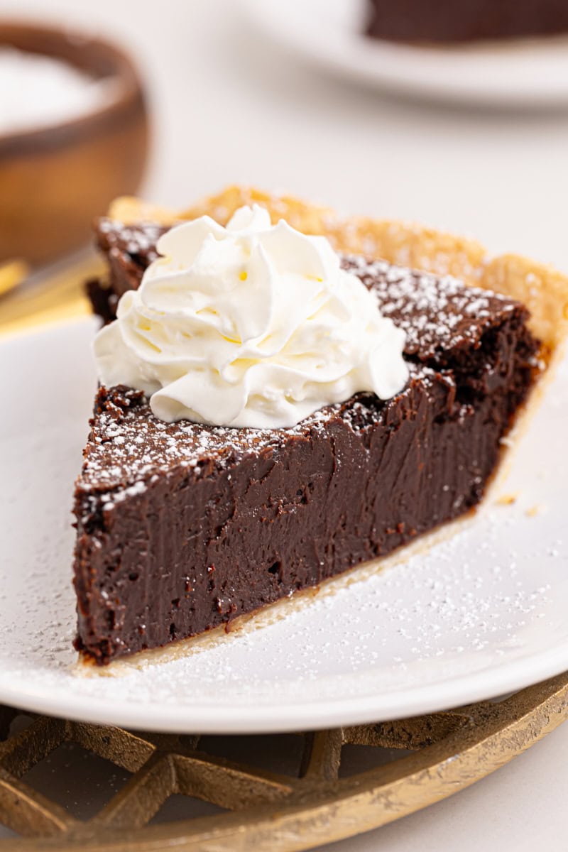 a slice of hot fudge pie topped with powdered sugar and whipped cream