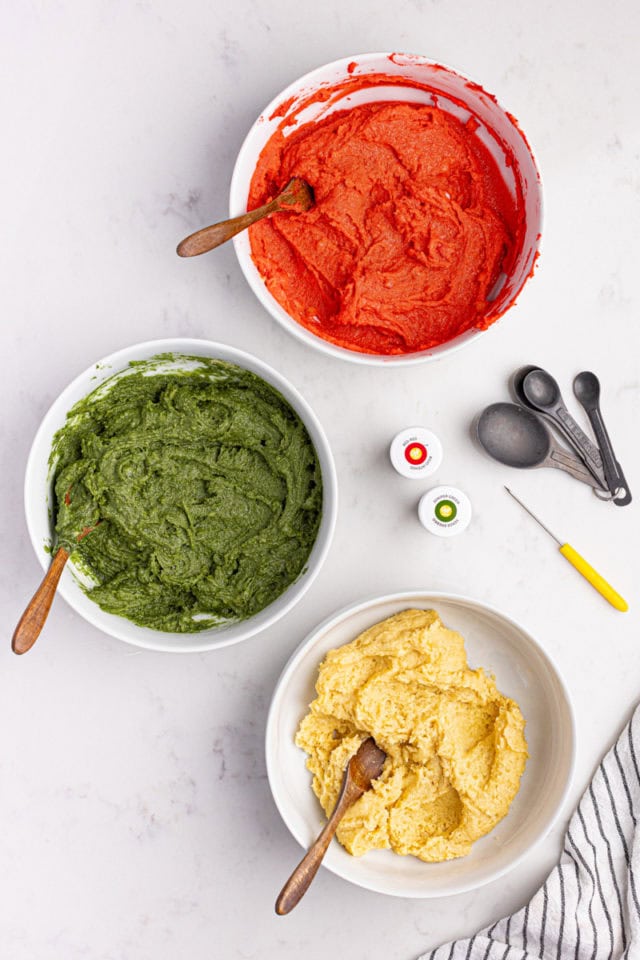 overhead view of three portions of Italian rainbow cookie dough—plain, tinted green, and tinted red