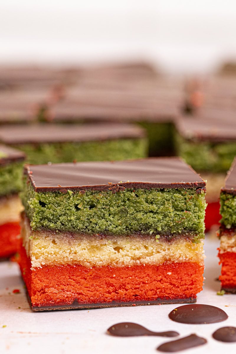 close-up of an Italian rainbow cookie with more cookies surrounding it