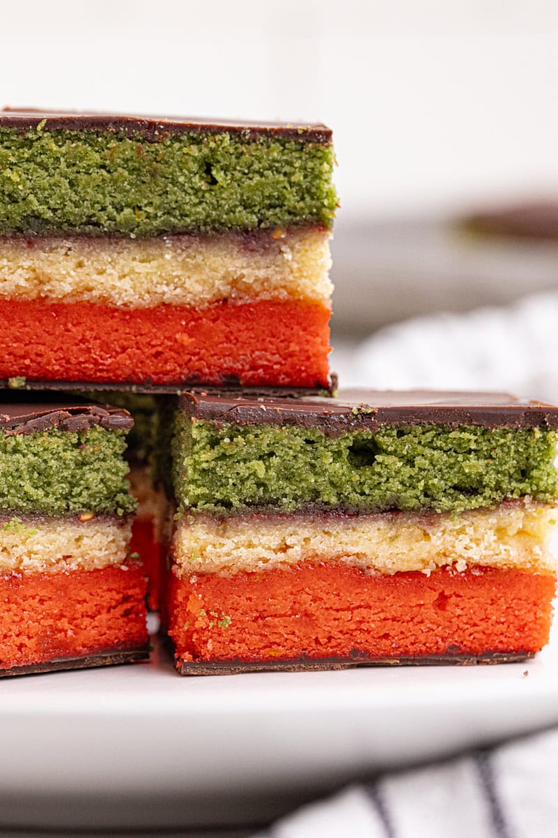 close-up of three Italian rainbow cookies on a white plate