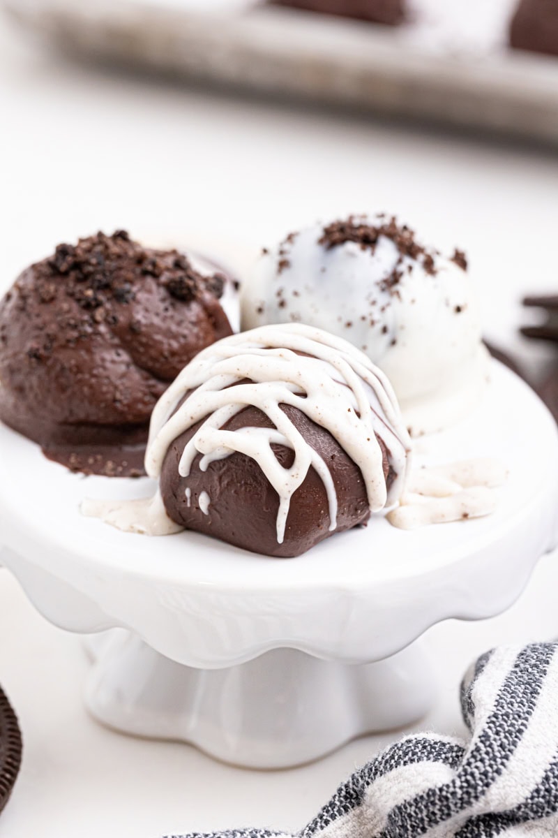 three Oreo truffles on a small white pedestal