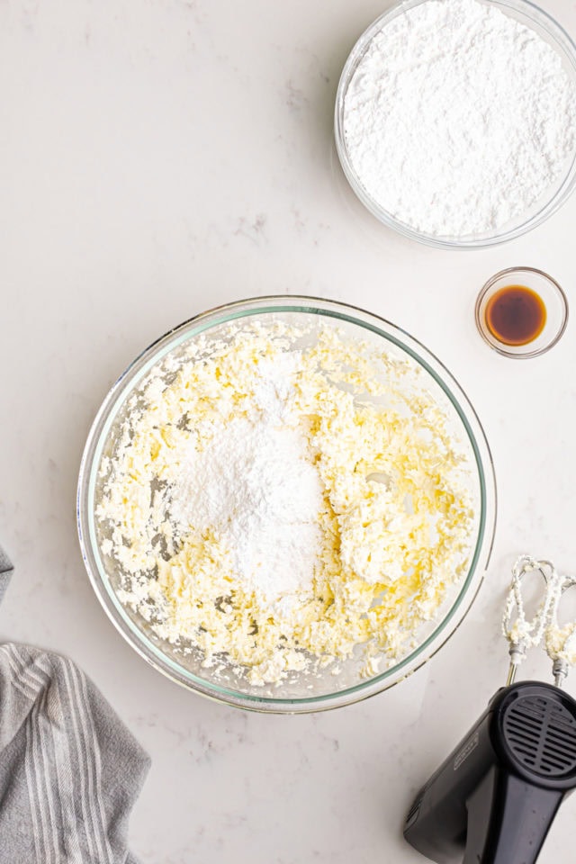 overhead view of confectioners' sugar added to creamed butter and cream cheese