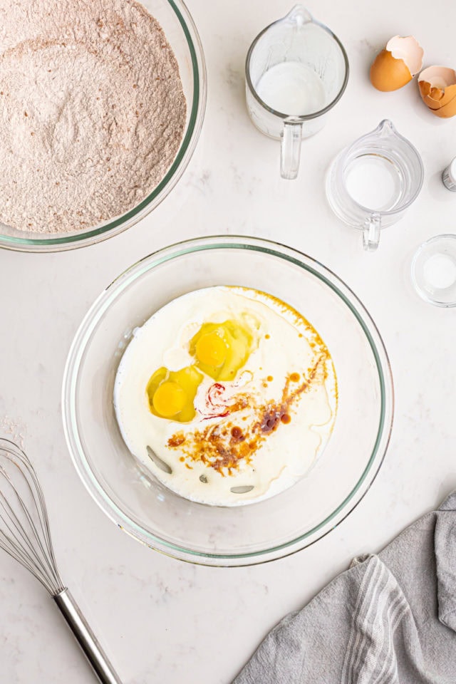 overhead view of buttermilk, oil, eggs, red food coloring, vinegar, and vanilla in a mixing bowl