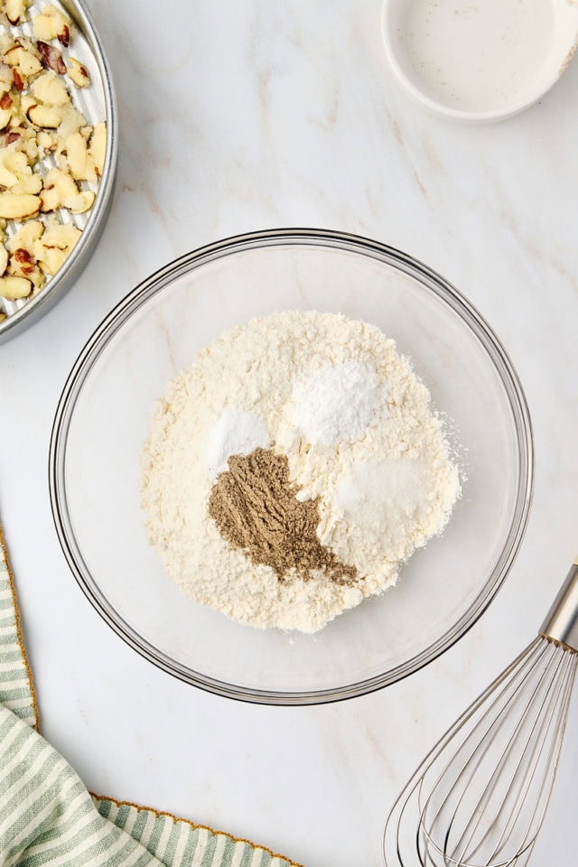 overhead view of flour, baking powder, baking soda, salt, and cardamom in a mixing bowl