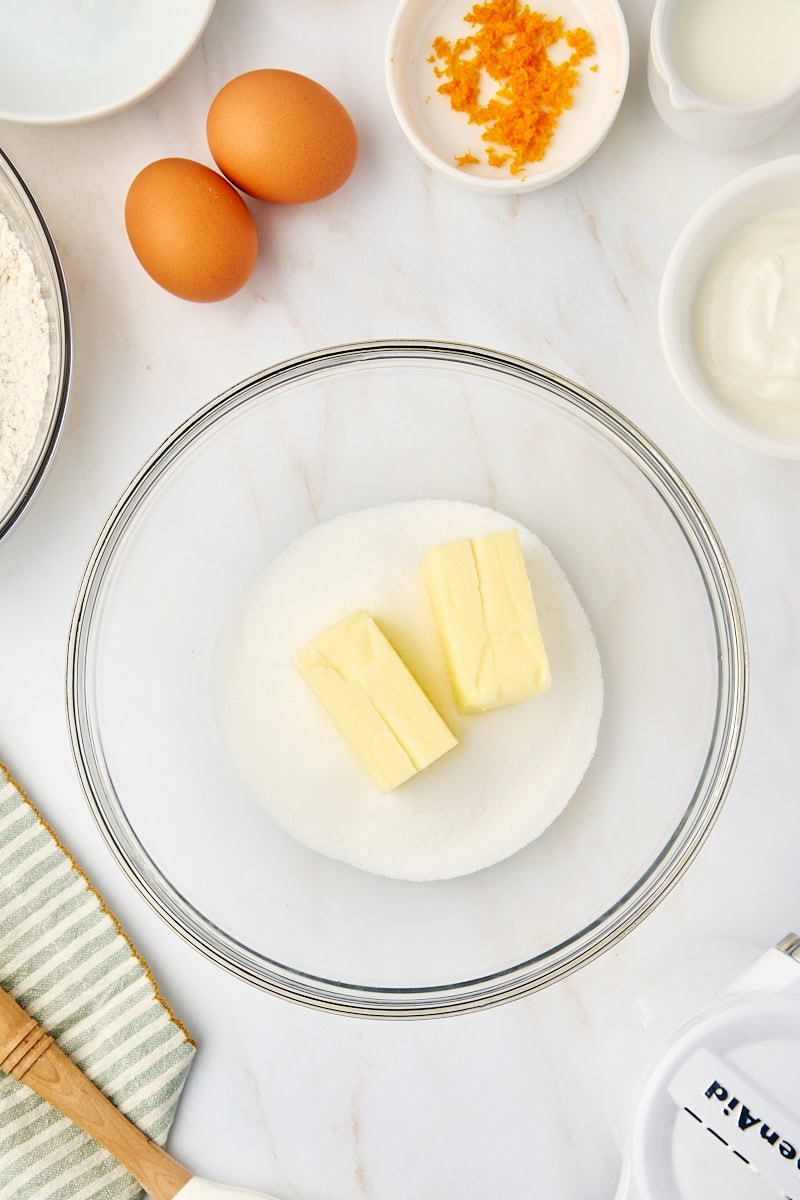 Overhead view of softened butter and granulated sugar being creamed together in a mixing bowl until light and fluffy.