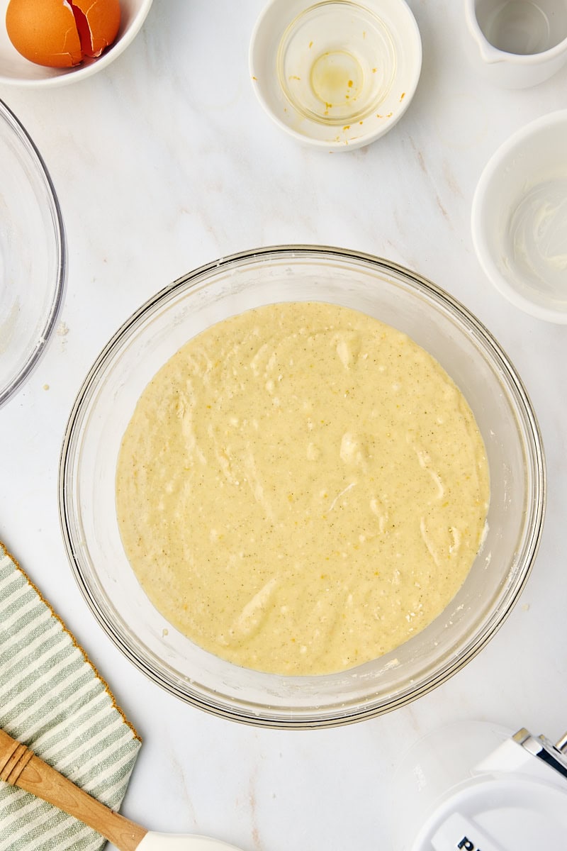 Overhead view of the fully mixed cardamom cake batter in a clear glass mixing bowl, showcasing its smooth consistency, ready for baking.