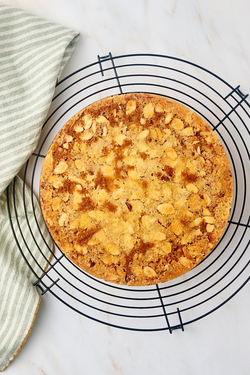 Overhead view of the cardamom cake, inverted onto a wire rack, cooling completely and showcasing its beautiful almond topping.