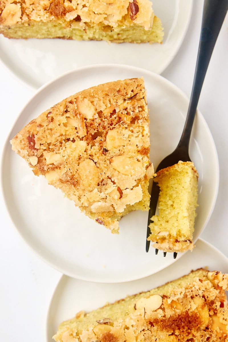 overhead view of a slice of cardamom cake on a white plate with a bite on a fork