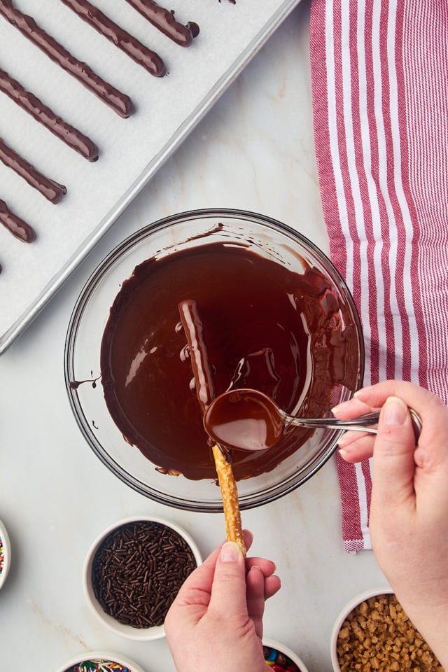 overhead view of a pretzel rod being coated in dark chocolate