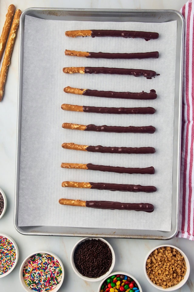 overhead view of chocolate covered pretzel rods on a baking sheet