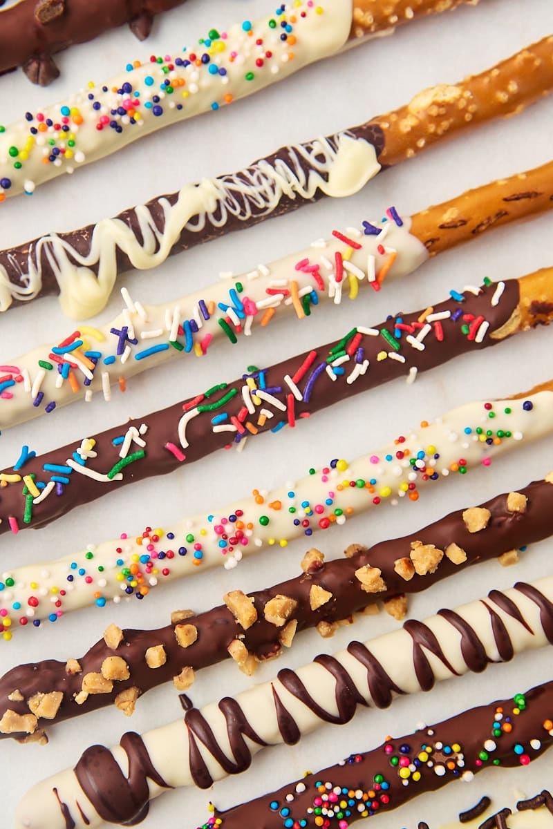 overhead view of several chocolate covered pretzel rods lined up on parchment paper