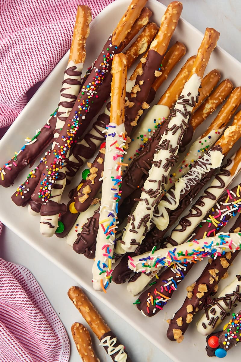 overhead view of several chocolate covered pretzel rods on a white serving tray