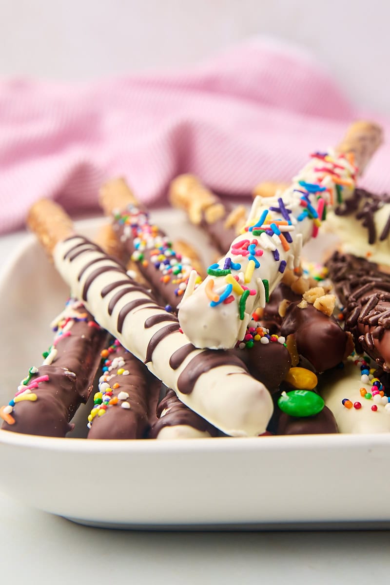 chocolate covered pretzel rods on a white serving tray