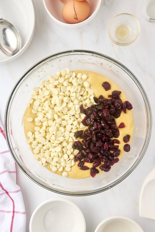 overhead view of white chocolate chips and dried cranberries added to cranberry bliss bar batter