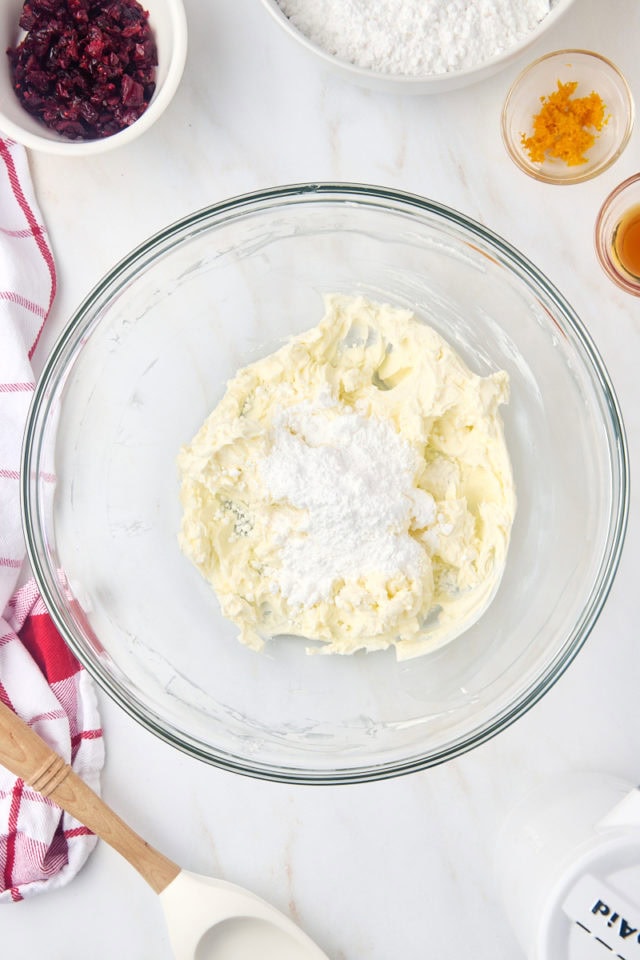 overhead view of confectioners' sugar added to beaten cream cheese