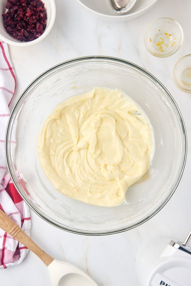 overhead view of orange cream cheese frosting in a mixing bowl